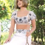 Woman with short bob wig on a swing in a garden setting.
